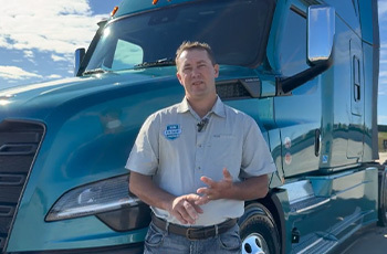 A man standing next to a teal Freightliner.